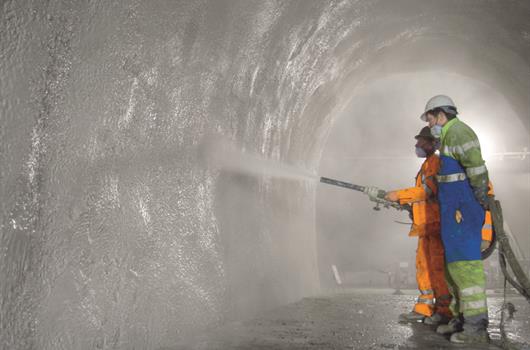 Construction workers spraying concrete in a tunnel.