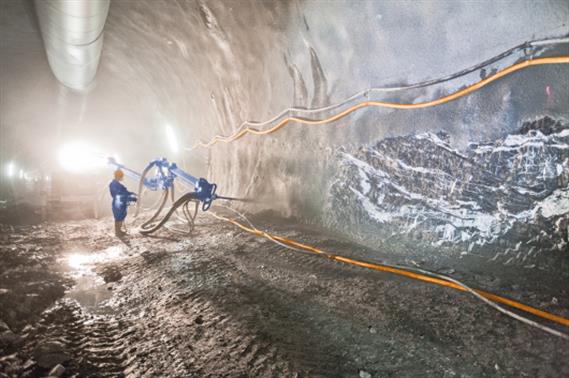 Construction worker spraying of concrete with a machine in a tunnel
